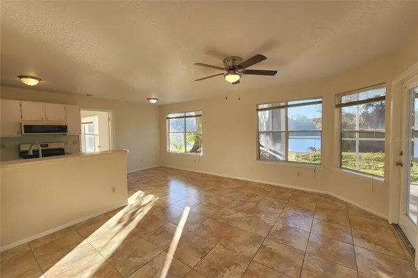 a view of a livingroom with a fireplace a ceiling fan and windows