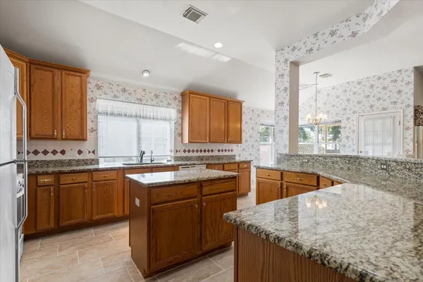 a kitchen with stainless steel appliances granite countertop wooden cabinets a sink and dishwasher a refrigerator