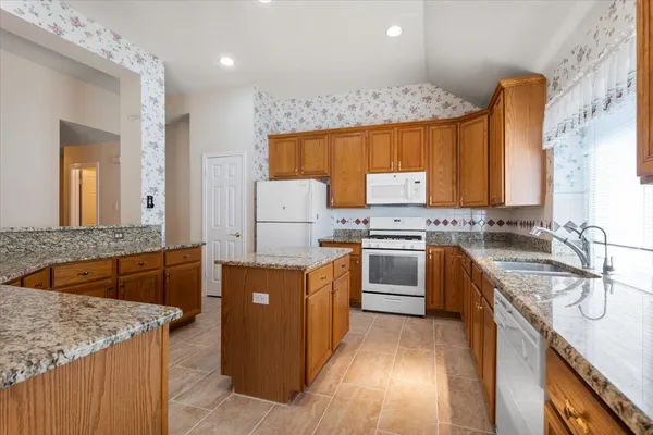 a kitchen with granite countertop a sink stove and refrigerator