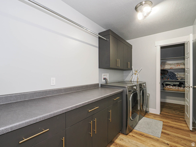 2487 Canyon Wild Road, Unit 413 Draper, UT 84020 - Photo 41 of 75 Laundry room with light wood-style floors, cabinet space, washer and clothes dryer, and a textured ceiling