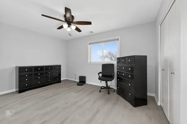 a bedroom with a dresser and a ceiling fan
