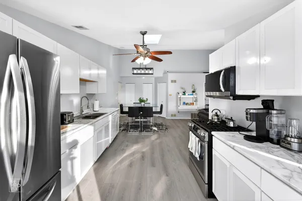 a kitchen with stainless steel appliances granite countertop a sink refrigerator stove and microwave