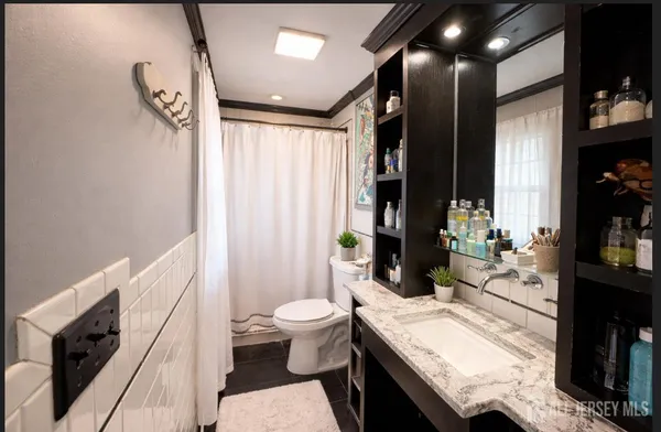 a bathroom with a granite countertop sink a toilet a mirror and shower