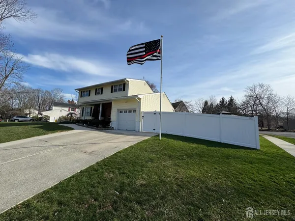 a view of a house with a yard and a car park