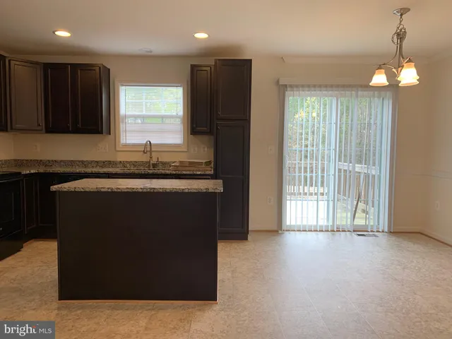 a kitchen with kitchen island granite countertop a stove a sink a refrigerator and a dining table with wooden floor