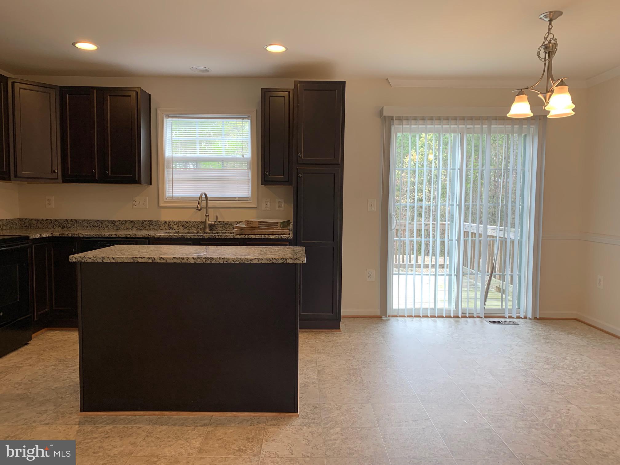 10421 Westgate Court Ruther Glen, VA 22546 - Photo 4 of 13 a kitchen with kitchen island granite countertop a stove a sink a refrigerator and a dining table with wooden floor