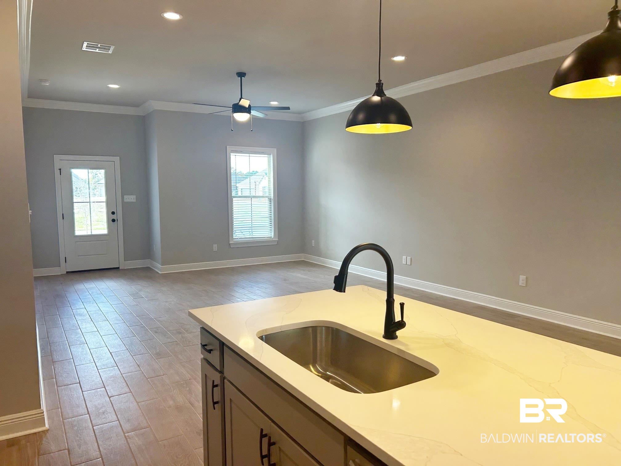 808 Sumter Loop Foley, AL 36535 - Photo 5 of 18 Kitchen featuring sink, light stone counters, light hardwood / wood-style flooring, decorative light fixtures, and ornamental molding