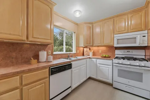 a kitchen with granite countertop white cabinets and white appliances