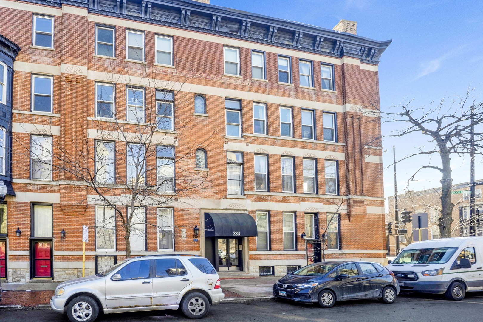 a front view of a building with cars parked
