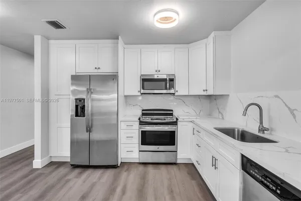 a kitchen with stainless steel appliances a refrigerator sink and white cabinets