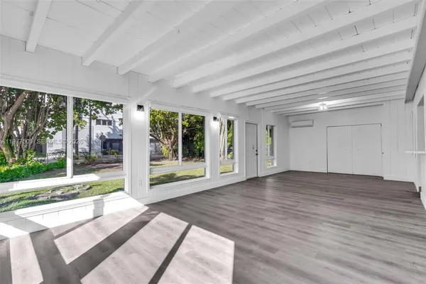 a view of an empty room with wooden floor and a floor to ceiling window
