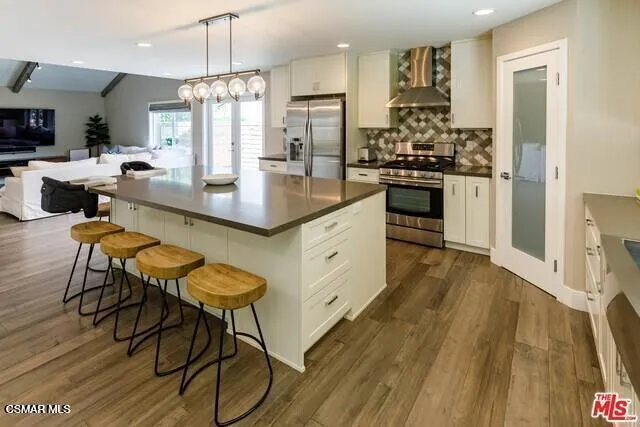 a kitchen with stainless steel appliances kitchen island granite countertop wooden floors and white cabinets