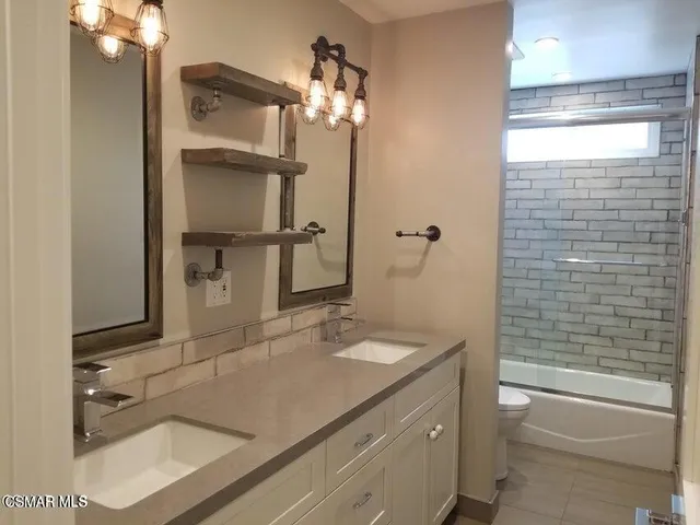 a bathroom with a granite countertop sink a toilet and shower
