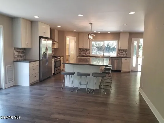 a kitchen with stainless steel appliances kitchen island granite countertop a refrigerator and a stove top oven