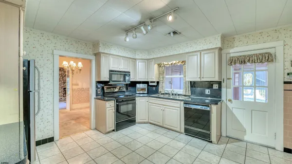 a kitchen with stainless steel appliances granite countertop a stove top oven a sink dishwasher a refrigerator and a microwave oven with white cabinets