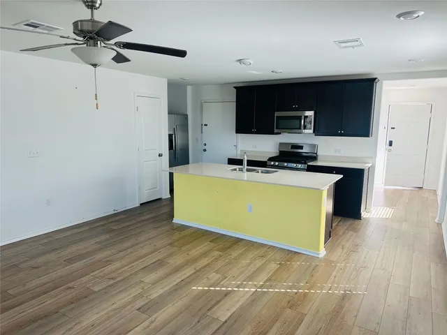 a view of kitchen with stainless steel appliances granite countertop a sink and a stove with wooden floor