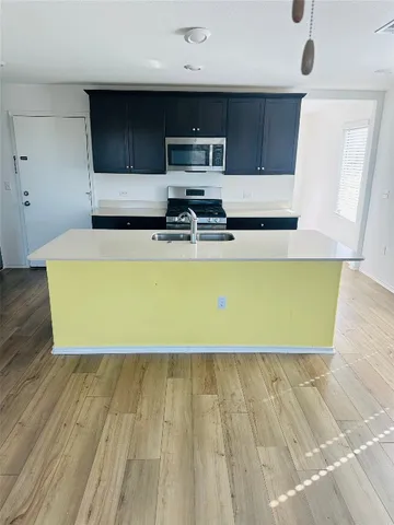 a living room with wooden floor table and kitchen view