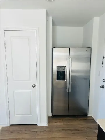 a view of a refrigerator in kitchen with stainless steel appliances wooden floor