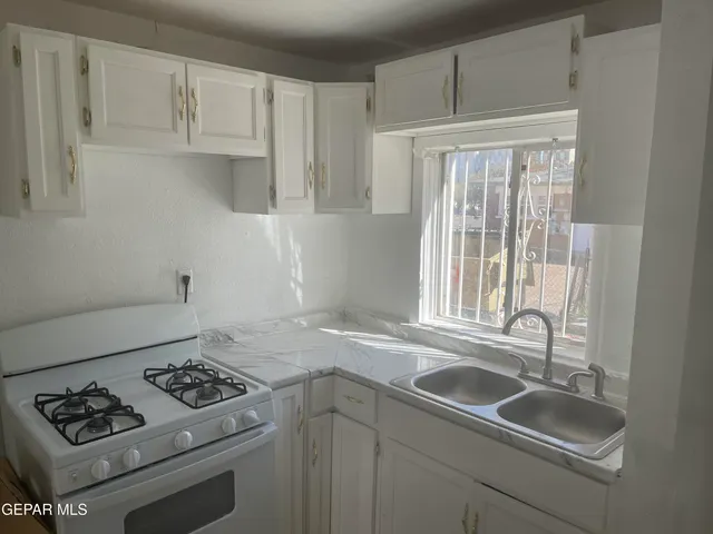a kitchen with sink a stove and cabinets