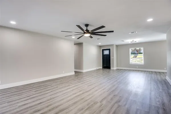 a view of an empty room with wooden floor and a window