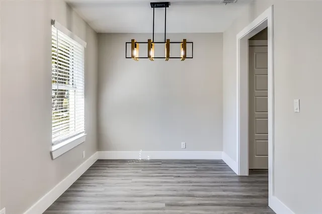 a view of an empty room with wooden floor and windows