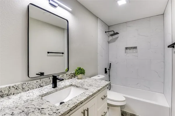 a bathroom with a granite countertop sink toilet and shower