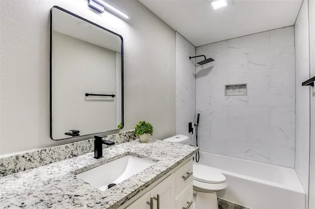 a bathroom with a granite countertop sink toilet and shower