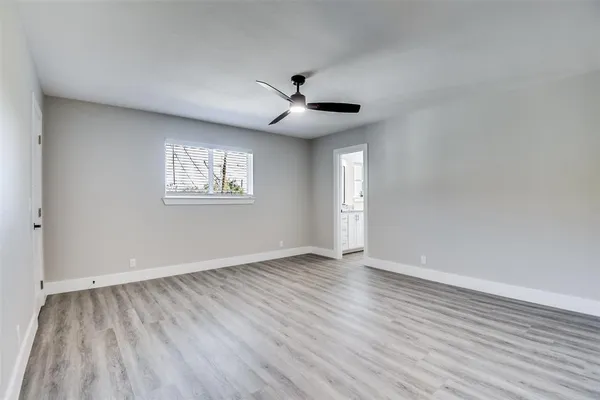 an empty room with wooden floor ceiling fan and windows