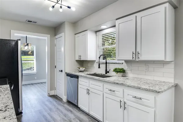 a kitchen with granite countertop stainless steel appliances white cabinets and wooden floor