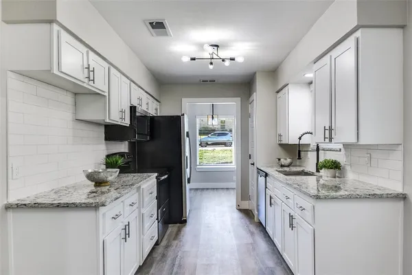 a kitchen with granite countertop a sink stove refrigerator and cabinets