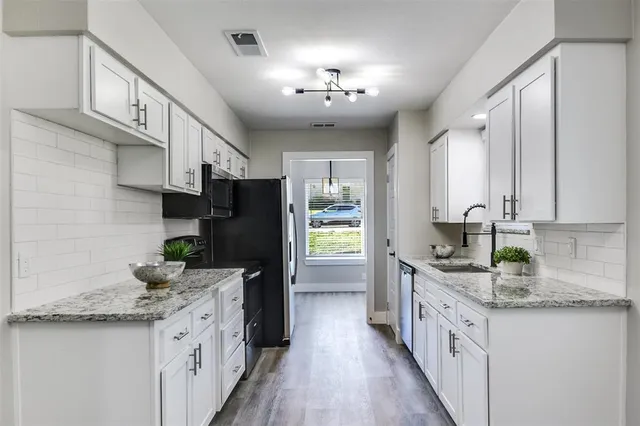 a kitchen with granite countertop a sink stove refrigerator and cabinets