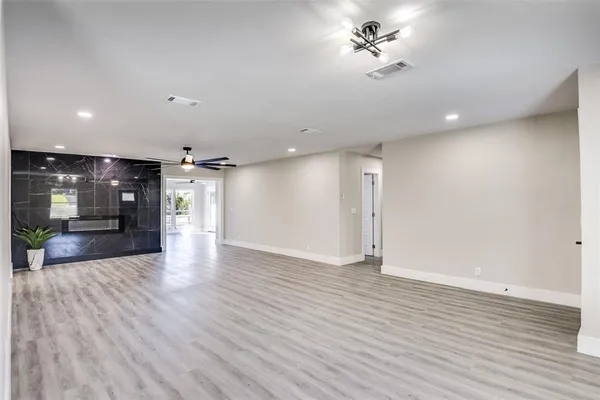an empty room with wooden floor ceiling fan and windows