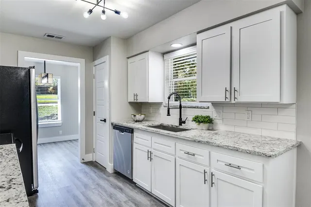 a kitchen with granite countertop stainless steel appliances white cabinets and wooden floor