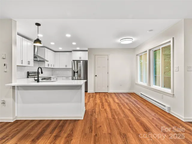 a kitchen with stainless steel appliances granite countertop a sink cabinets and wooden floor