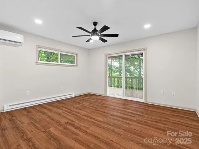an empty room with wooden floor fan and windows