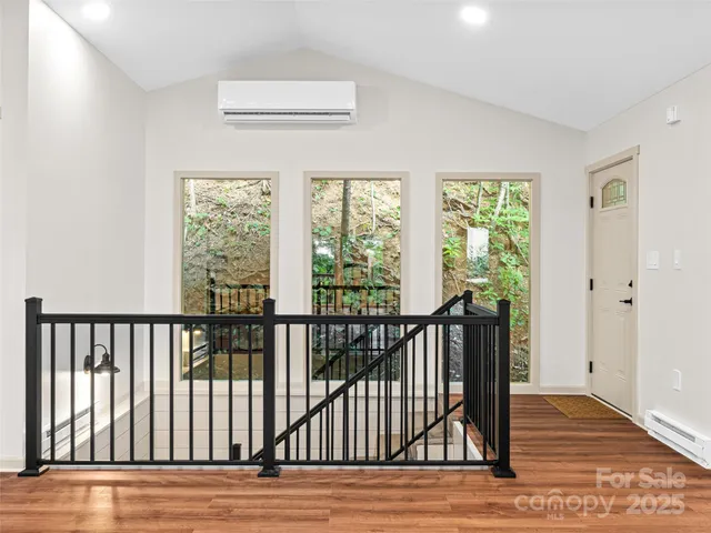 a view of an empty room and a kitchen with wooden floor and a fireplace