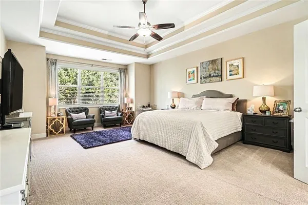 a spacious bedroom with a bed a couch and a flat tv screen