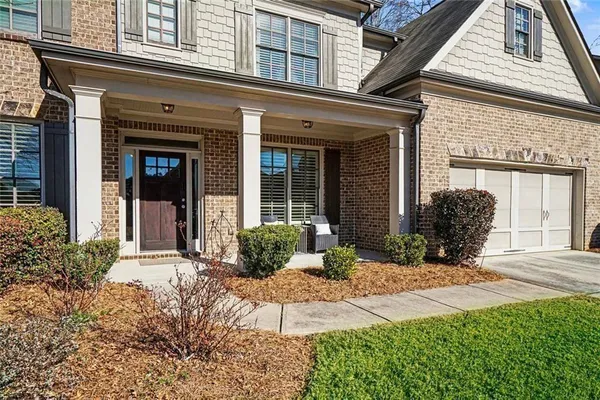front view of a brick house with a large window and potted plants