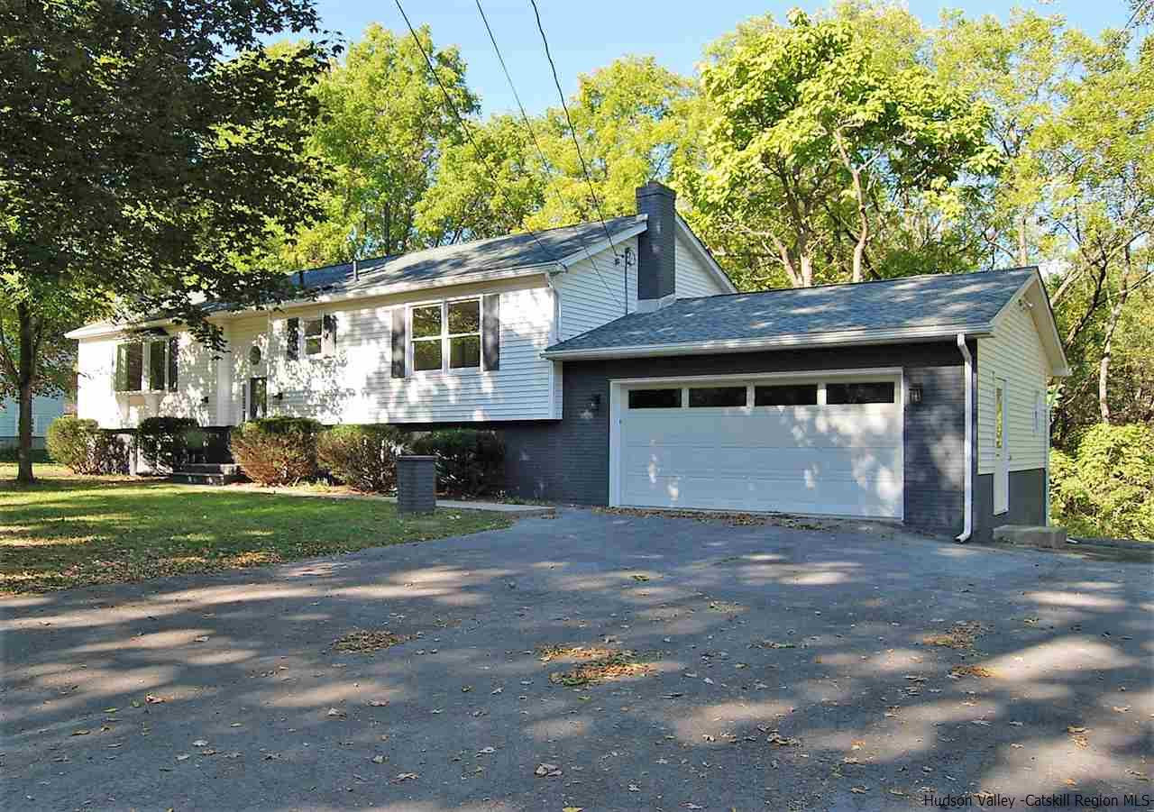 a front view of a house with a garden and trees