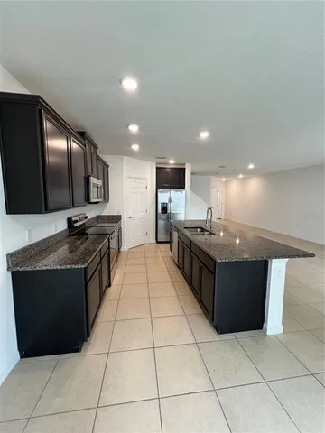 a large kitchen with kitchen island granite countertop a sink and a stove top oven