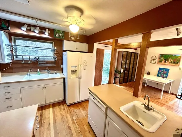 a kitchen with stainless steel appliances granite countertop a refrigerator a sink and white cabinets