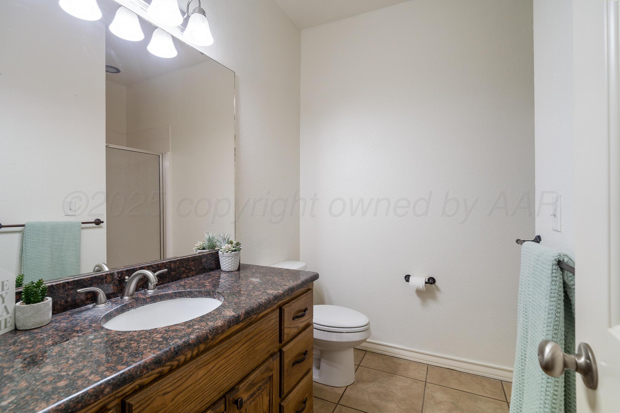 18451 Copper Ridge Bushland, TX 79124 - Photo 25 of 50 a bathroom with a granite countertop sink a toilet and a mirror