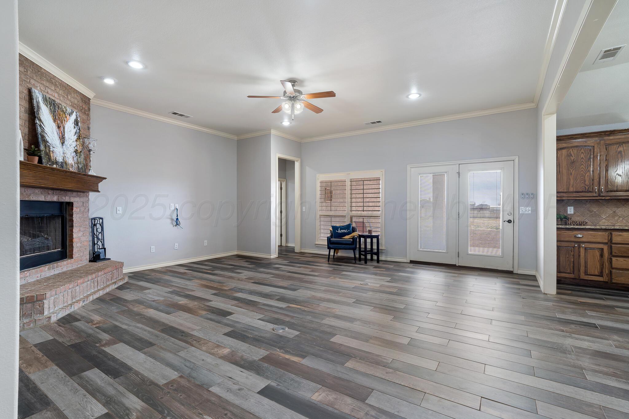18451 Copper Ridge Bushland, TX 79124 - Photo 7 of 50 a view of a livingroom with a fireplace a chandelier wooden floor and windows