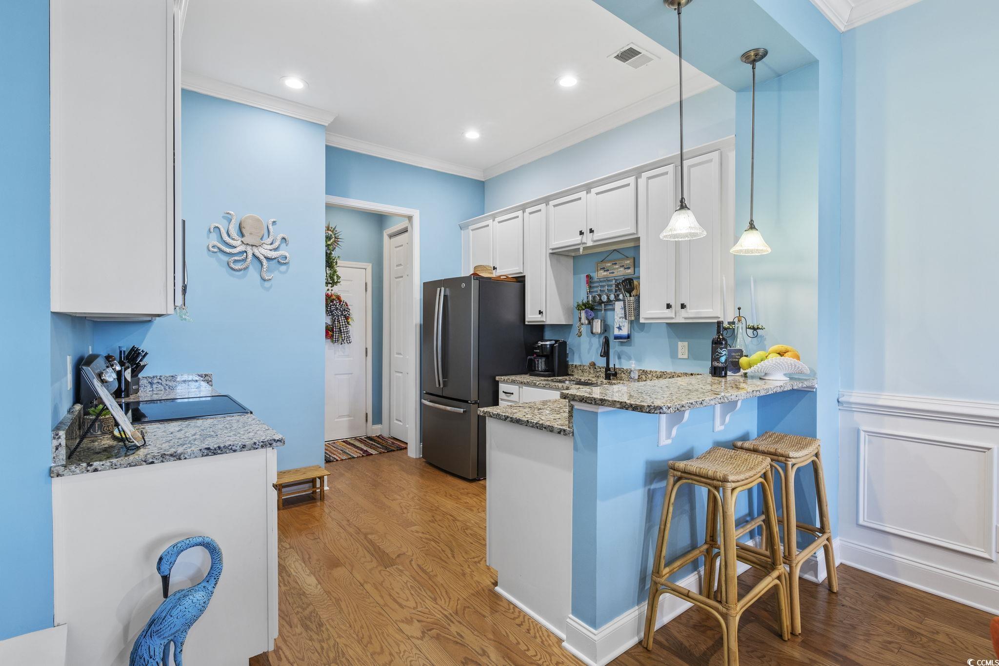 718 Shine Avenue, Unit 718 Myrtle Beach, SC 29577 - Photo 13 of 36 Kitchen with white cabinetry, crown molding, light stone counters, pendant lighting, and a breakfast bar area