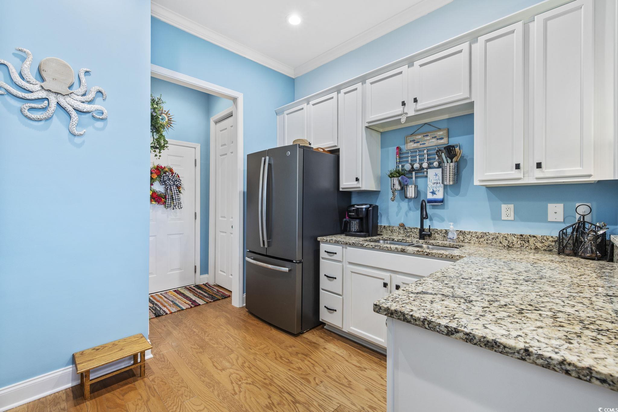 718 Shine Avenue, Unit 718 Myrtle Beach, SC 29577 - Photo 14 of 36 Kitchen featuring light stone countertops, freestanding refrigerator, white cabinetry, light wood-type flooring, and crown molding