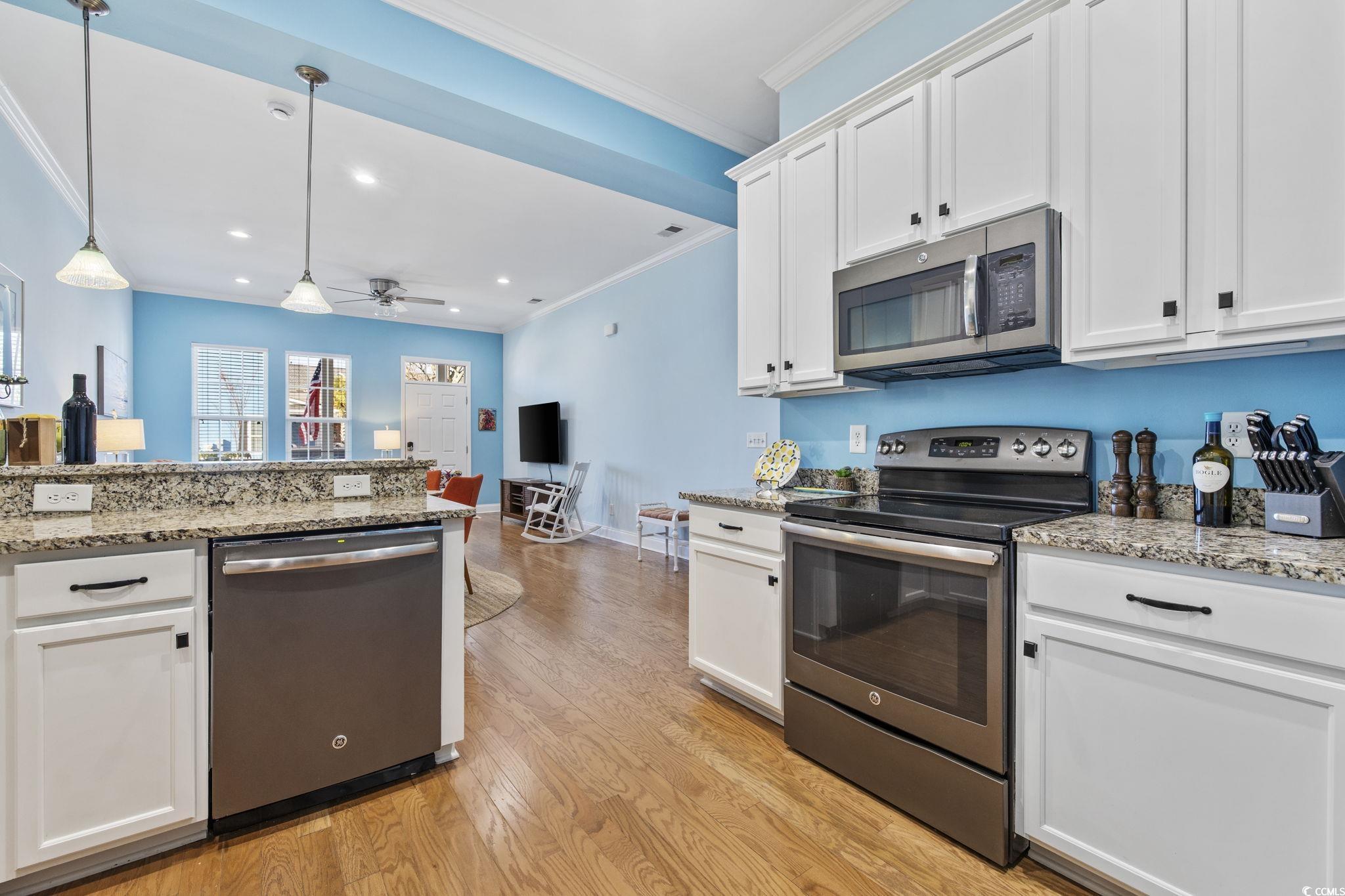 718 Shine Avenue, Unit 718 Myrtle Beach, SC 29577 - Photo 15 of 36 Kitchen with stainless steel appliances, white cabinetry, pendant lighting, light stone counters, and crown molding