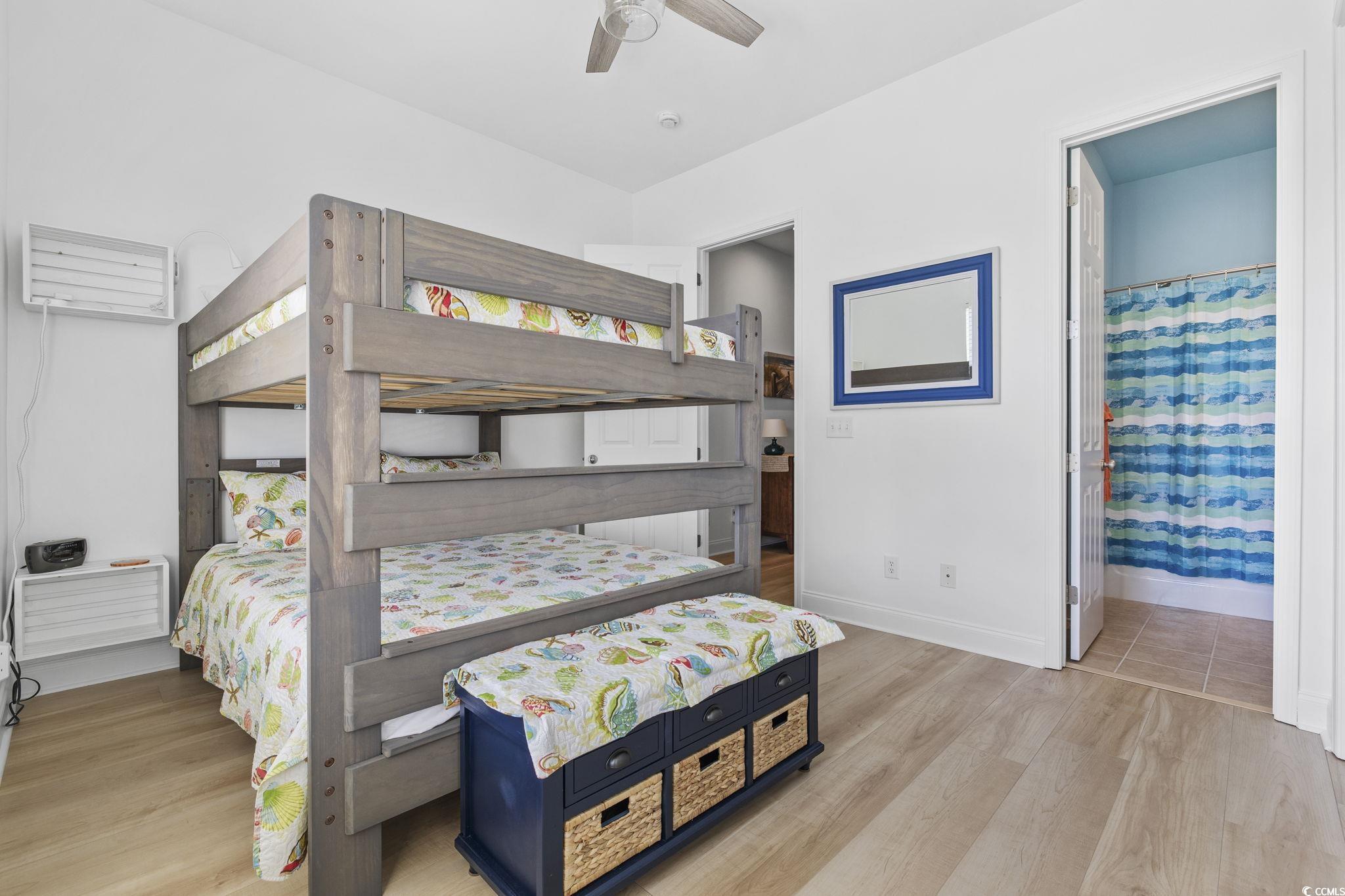 718 Shine Avenue, Unit 718 Myrtle Beach, SC 29577 - Photo 29 of 36 Bedroom featuring light wood finished floors, a ceiling fan, ensuite bath, and an AC wall unit