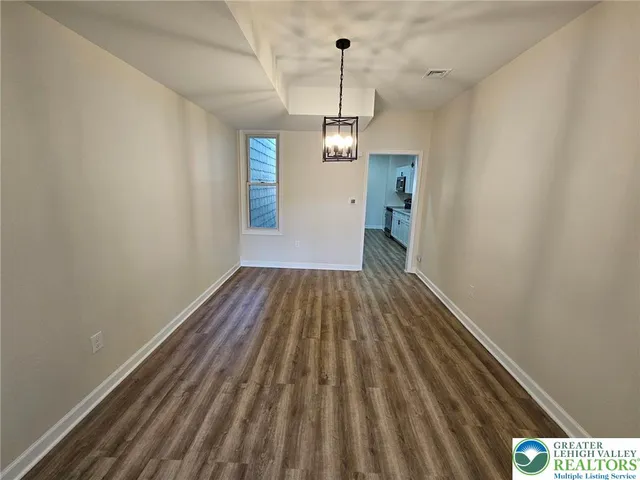 a view of a room with wooden floor a ceiling fan and window