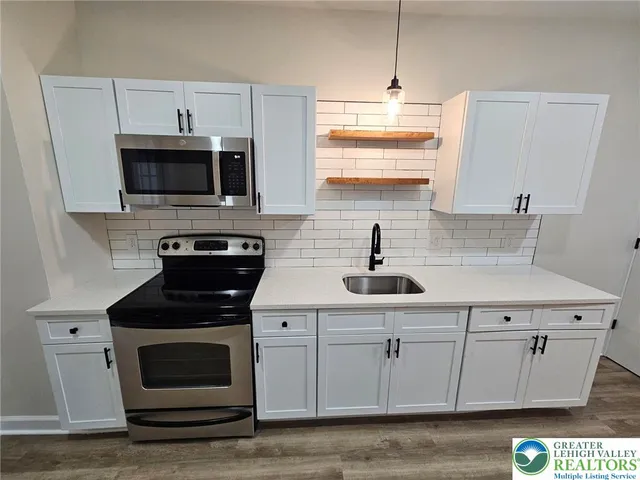 a kitchen with stainless steel appliances granite countertop a sink a stove a microwave and wooden cabinets