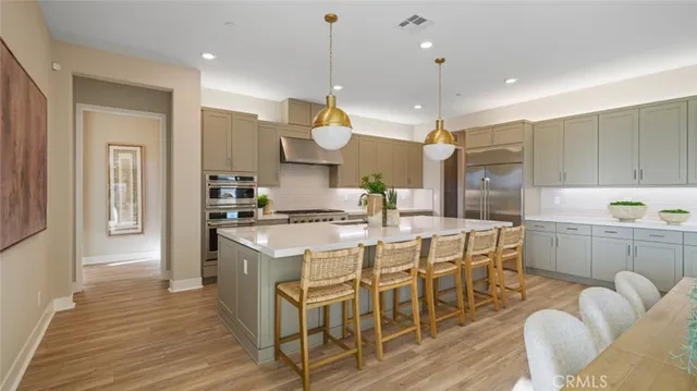 a kitchen with stainless steel appliances granite countertop a sink a stove a refrigerator and island with wooden floor